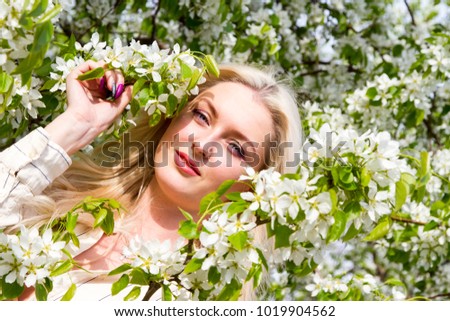 Blonde in the garden, among the flowering trees
