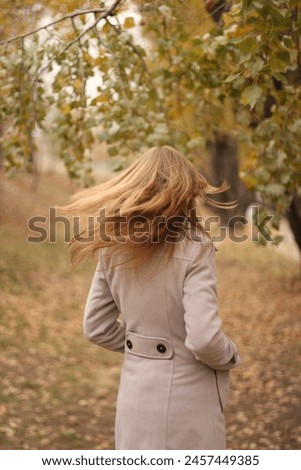 Blonde girl in a coat and black boots in autumn