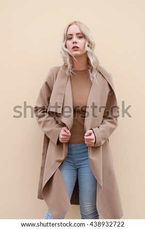 Blonde girl in the coat posing outside