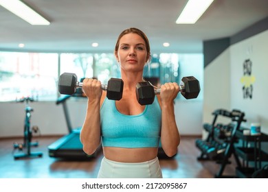 blonde girl doing biceps curls at the gym