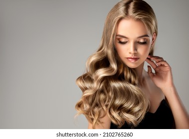 Blonde girl with long  and   shiny wavy hair .  Beautiful  woman model with curly hairstyle . - Shutterstock ID 2102765260