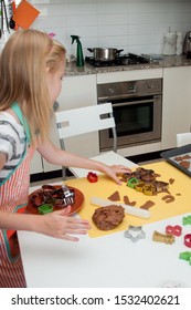 A blonde girl making Chritstmas gingerbread cookie with various cookie cutters