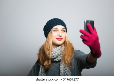 blonde girl making funny self photo on the phone, Christmas concept, studio photo isolated on a gray background
