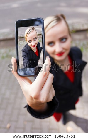 Blonde girl making a selfshot with smartphone.