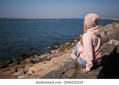 a blonde girl on the background of a cold sea, seagulls in the sky. travel and travel concept, immigration. girl pouring at the beach, casual outfit, backpacker, traveler, cold weat - Powered by Shutterstock