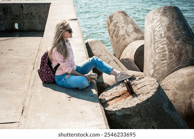 a blonde girl on the background of a cold sea, seagulls in the sky. travel and travel concept, immigration. girl pouring at the beach, casual outfit, backpacker, traveler, cold weat - Powered by Shutterstock