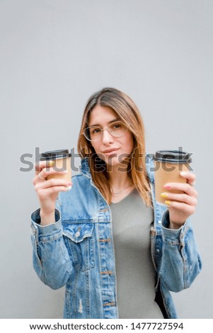 Blonde girl with paper cups of coffee on grey