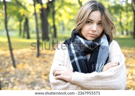 Blonde girl in a scarf in an autumn park with yellow leaves