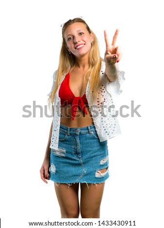 Blonde girl in summer vacation smiling and showing victory sign on isolated white background