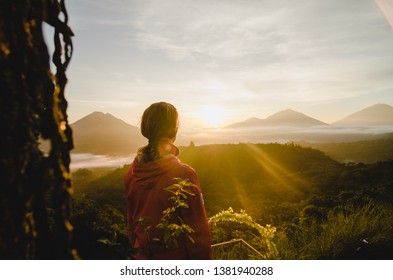 Blonde Girl Watching Sunrise At Viewpoint Over Batur Global Geopark, Kintamani, Bali, Indonesia