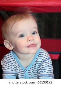 Blonde Haired, Blue Eyed, Caucasian Baby Boy With Cute Smiling Facial Expression Sits In Red Tent With Static Hair Standing On End