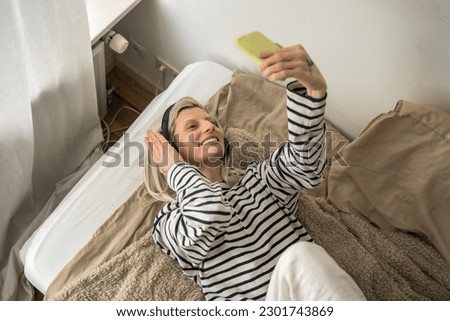 Blonde happy woman hearing song and looking at the smartphone camera