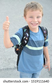 Blonde Kid With Blue Eyes Wearing A Backpack Giving Thumbs Up