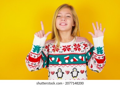 Blonde Kid Girl In White Knitted Sweater Christmas Over Yellow Background Showing And Pointing Up With Fingers Number Seven While Smiling Confident And Happy.