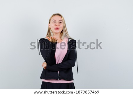  blonde lady sending air kiss with pouted lips in t-shirt, jacket and looking delicate. front view. 