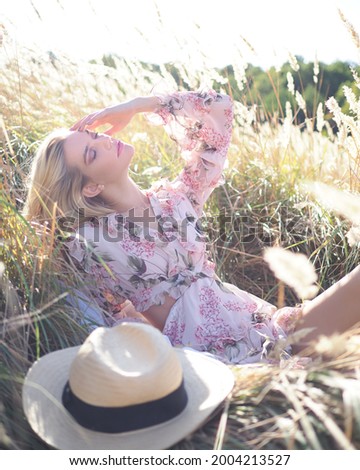 A blonde lies in a wheat field in a dress