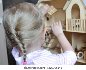 Blonde Little Girl Plays With Wooden Dollhouse