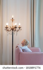 Blonde Little Girl Watching At The Lamp. Enjoy The Night Light. Cosy Living Room. 
Lighting Advertising Concept