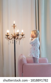 Blonde Little Girl Watching At The Lamp. Enjoy The Night Light. Cosy Living Room. 
Lighting Advertising Concept