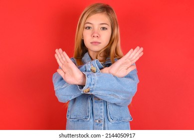 blonde little kid girl wearing denim jacket over red background  has rejection expression crossing arms and palms doing negative sign, angry face. - Shutterstock ID 2144050917