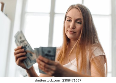 Blonde long-haired woman counting money at home
