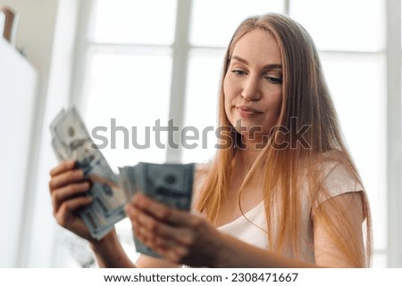 Blonde long-haired woman counting money at home