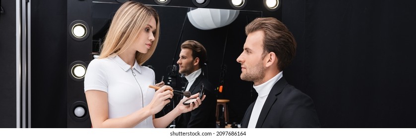 Blonde Makeup Artist Holding Cosmetic Brush And Face Powder Near Man In Makeup Room, Banner