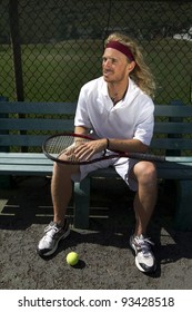 A Blonde Male Tennis Player Waits His Turn On The Sideline Bench