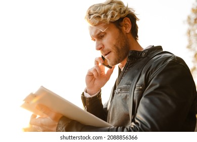 Blonde Man Talking On Mobile Phone While Working In Autumn Park