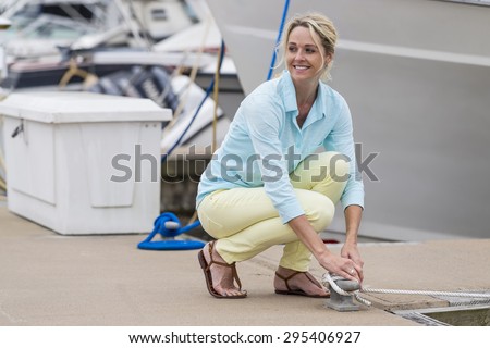 A blonde model posing outdoors with boats