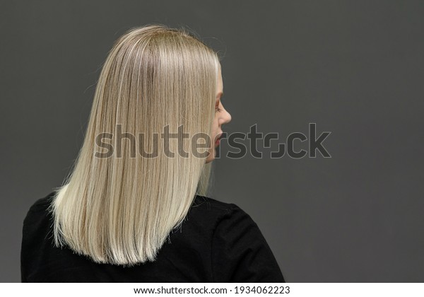 Blonde model with straight hair, look from\
behind. Hair bleaching result. Space for\
text