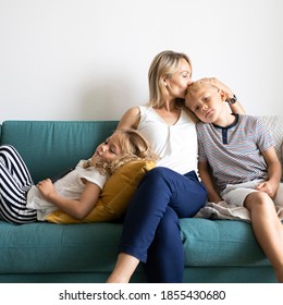 Blonde Mom Kissing Her Son’s Head And Relaxing With Daughter On The Couch