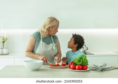 Blonde Mother And Her Son With Black Hair Together In White Kitchen At Home