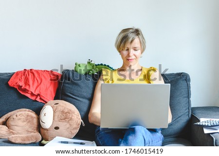blonde mother sitting in sofa and using laptop. Concept of Home office with children. Selective focus
