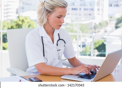 Blonde nurse in her office working on her laptop