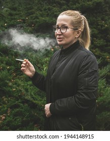 Blonde Polish Woman In Her 40s Smoking Cigarette Outside In The Forest. 