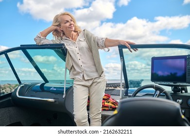 A blonde pretty woman standing on a boat deck and smiling