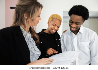 Blonde real estate agent explains the energy-saving features of the house as African American dark skinned couple looks on with keen interest impressed by the eco-friendly design happy family concept. - Powered by Shutterstock