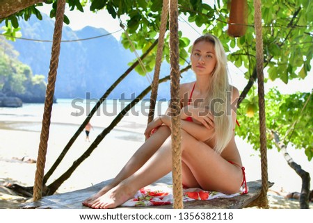 blonde in red swimsuit on beach swing