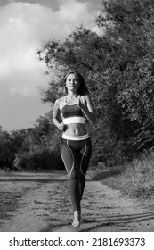 Blonde runner woman runs in the park joggin barefoot, black and white picture