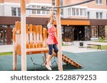 A blonde schoolgirl plays on the playground in the city