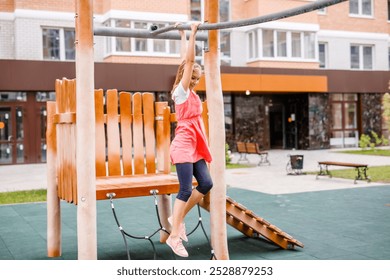 A blonde schoolgirl plays on the playground in the city's backyard. - Powered by Shutterstock