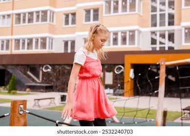 A blonde schoolgirl plays on the playground in the city's backyard. - Powered by Shutterstock