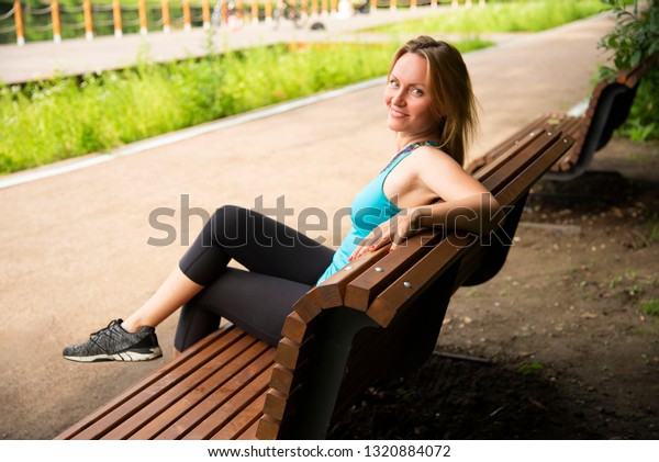 Blonde sports in the Park on the bench in the\
summer on the positive