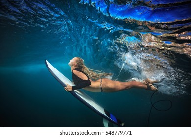 Blonde Surfer Girl In Bikini With Board Dive Under Big Ocean Wave Lip. Underwater Sport Activity With Fun. Family Lifestyle, Water Sport Lessons And Beach Swimming Activity On Summer Vacation