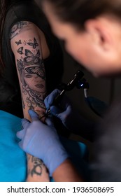 Blonde Tattoo Artist Tattooing A Portrait Of A Woman On The Left Arm In A Tattoo Studio