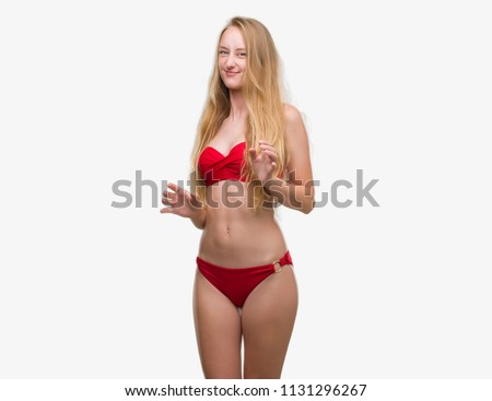 Blonde teenager woman wearing red bikini disgusted expression, displeased and fearful doing disgust face because aversion reaction. With hands raised. Annoying concept.
