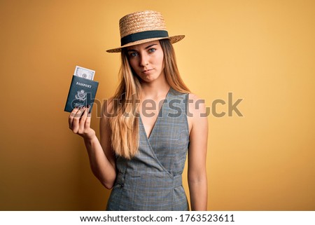 Blonde tourist woman with blue eyes on vacation holding united states passport with dollars with a confident expression on smart face thinking serious