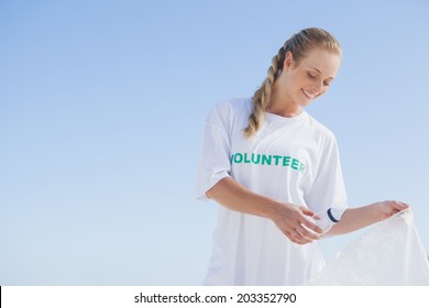 Blonde Volunteer Picking Up Trash On The Beach On A Sunny Day