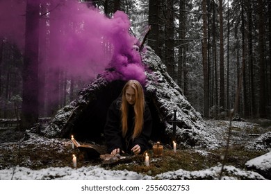 Blonde witch in a black coarse cassock sits on moss in a snowy forest and conjures. - Powered by Shutterstock